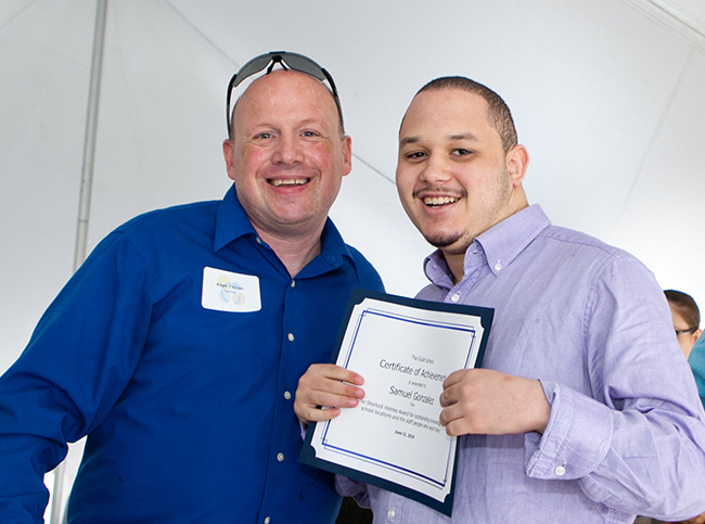 Student holds award and poses with teacher