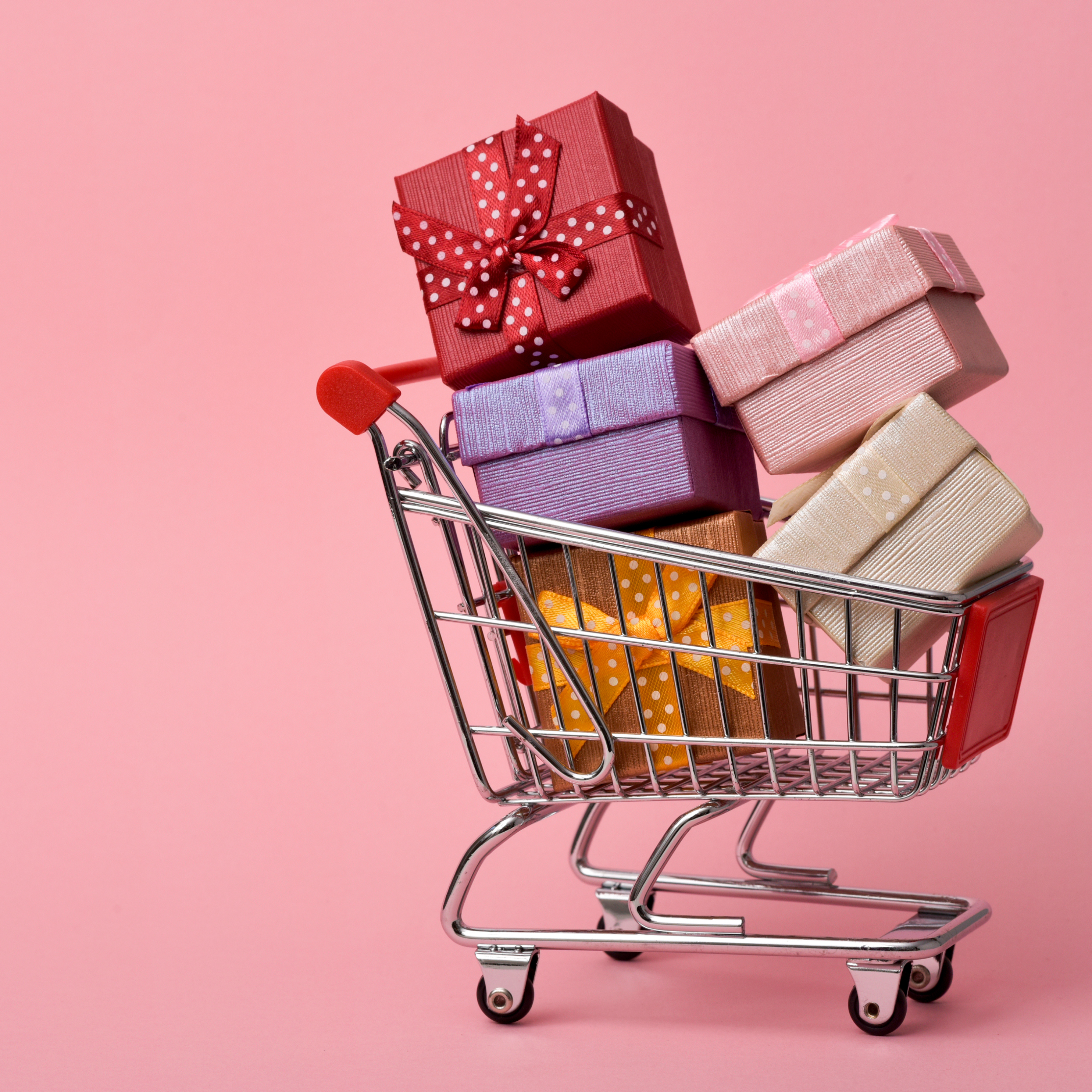 A shopping cart with gifts against a pink background