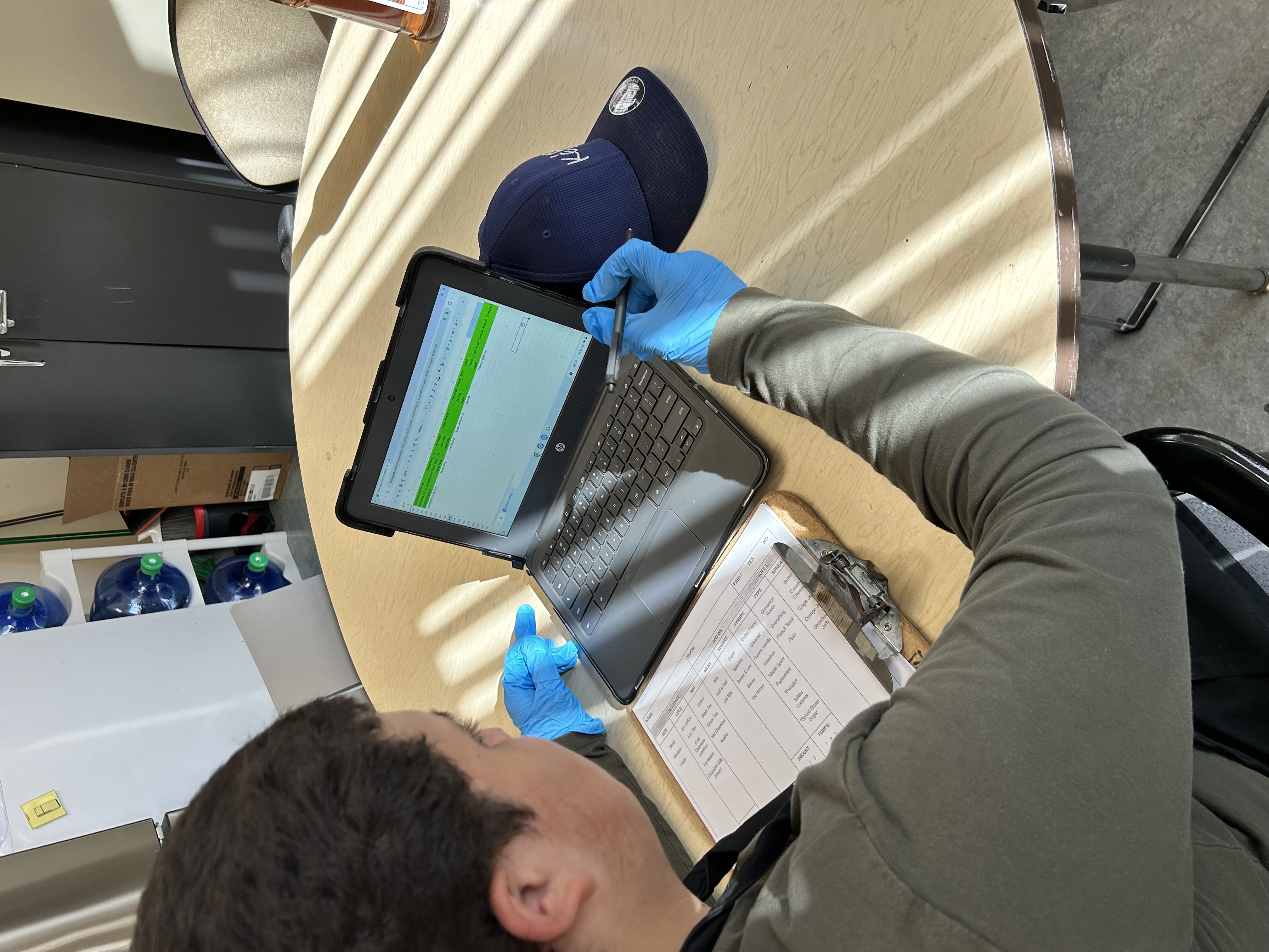 An over-the-shoulder look at a student processing a coffee shop order on a laptop.