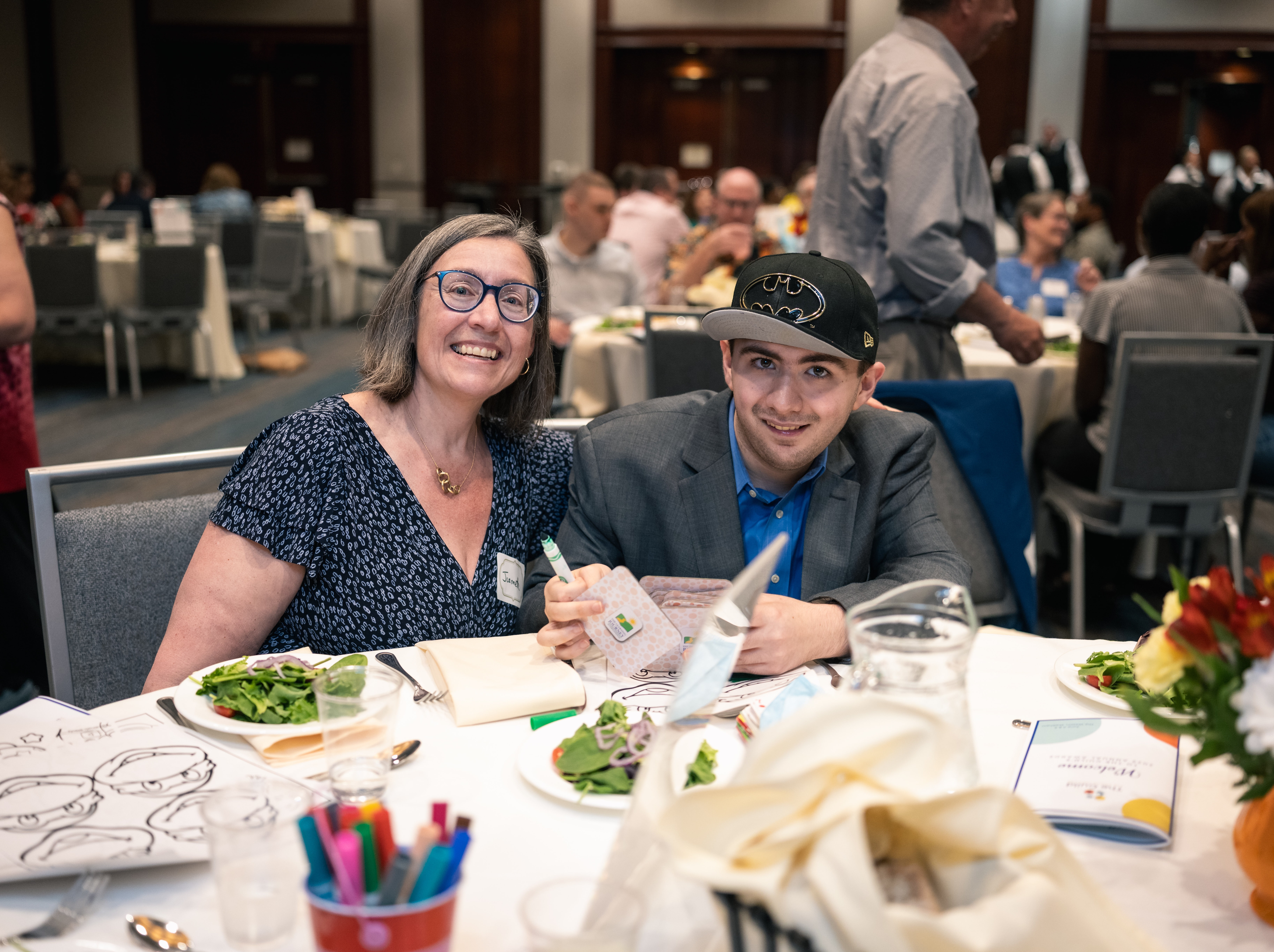 Jeannette and Robbie sit together at a formal dinner table.