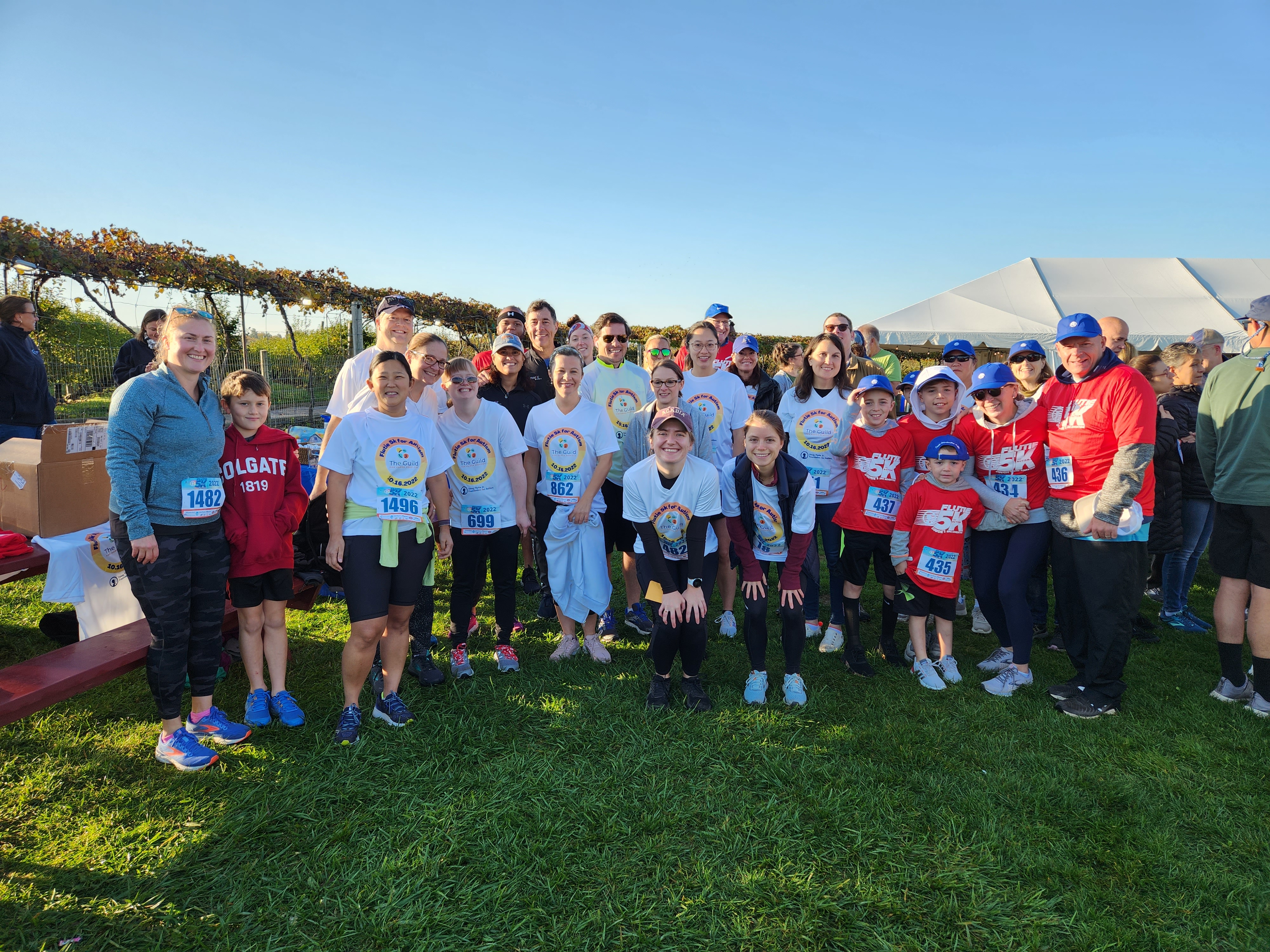 A large group of people on Team Guild gather together on a sunny morning at the Flutie 5K.