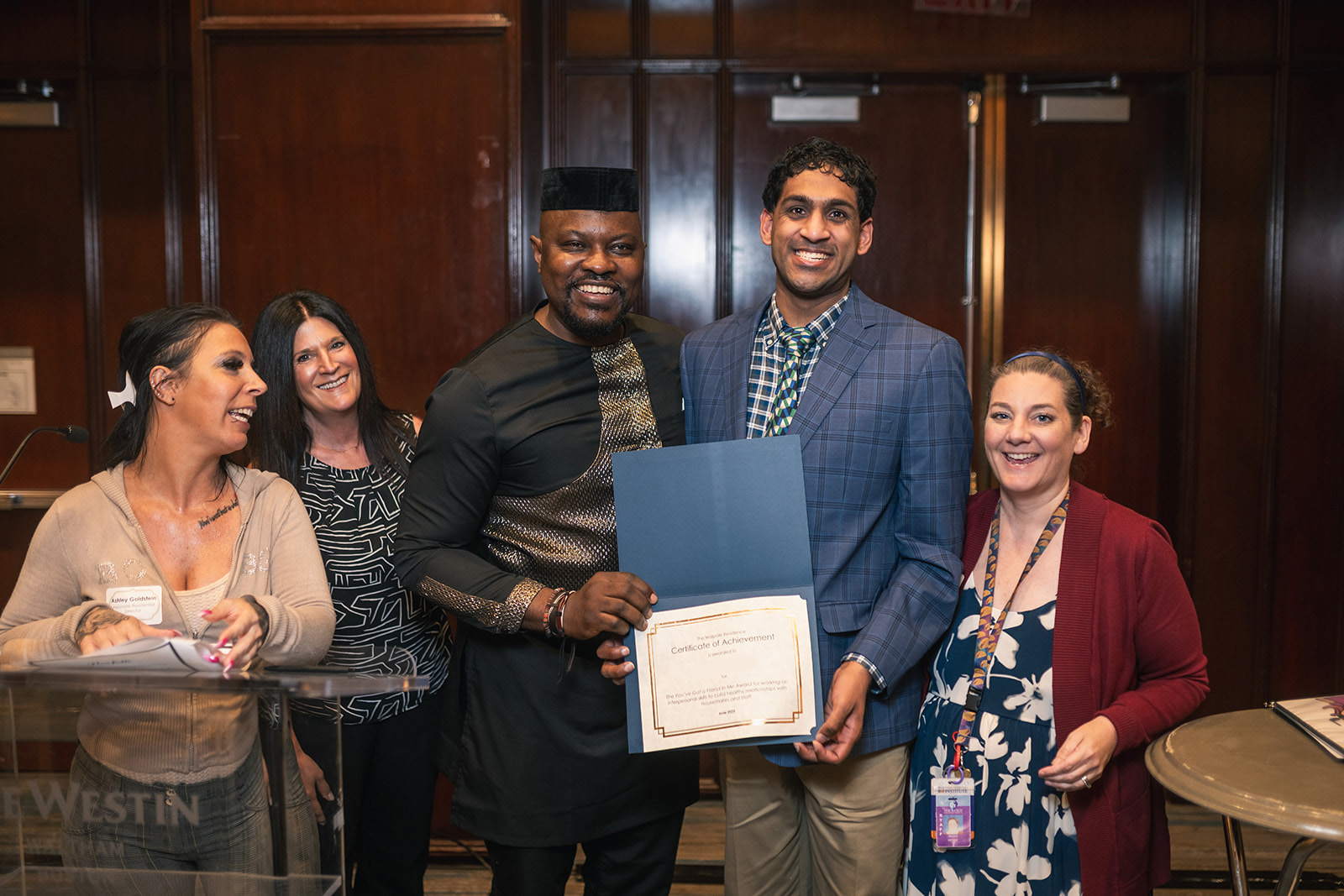 A Guild resident smiles with his house manager and other staff members as he accepts his award.