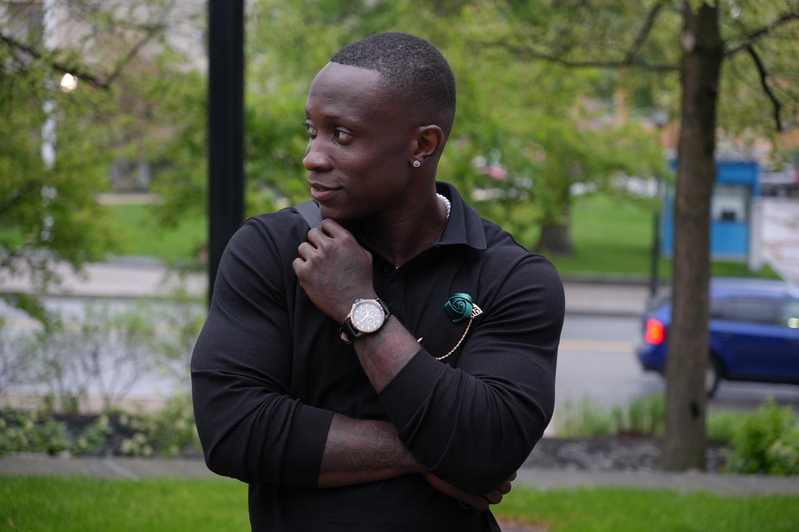McDouglas stands on a street outside, looking away from the camera