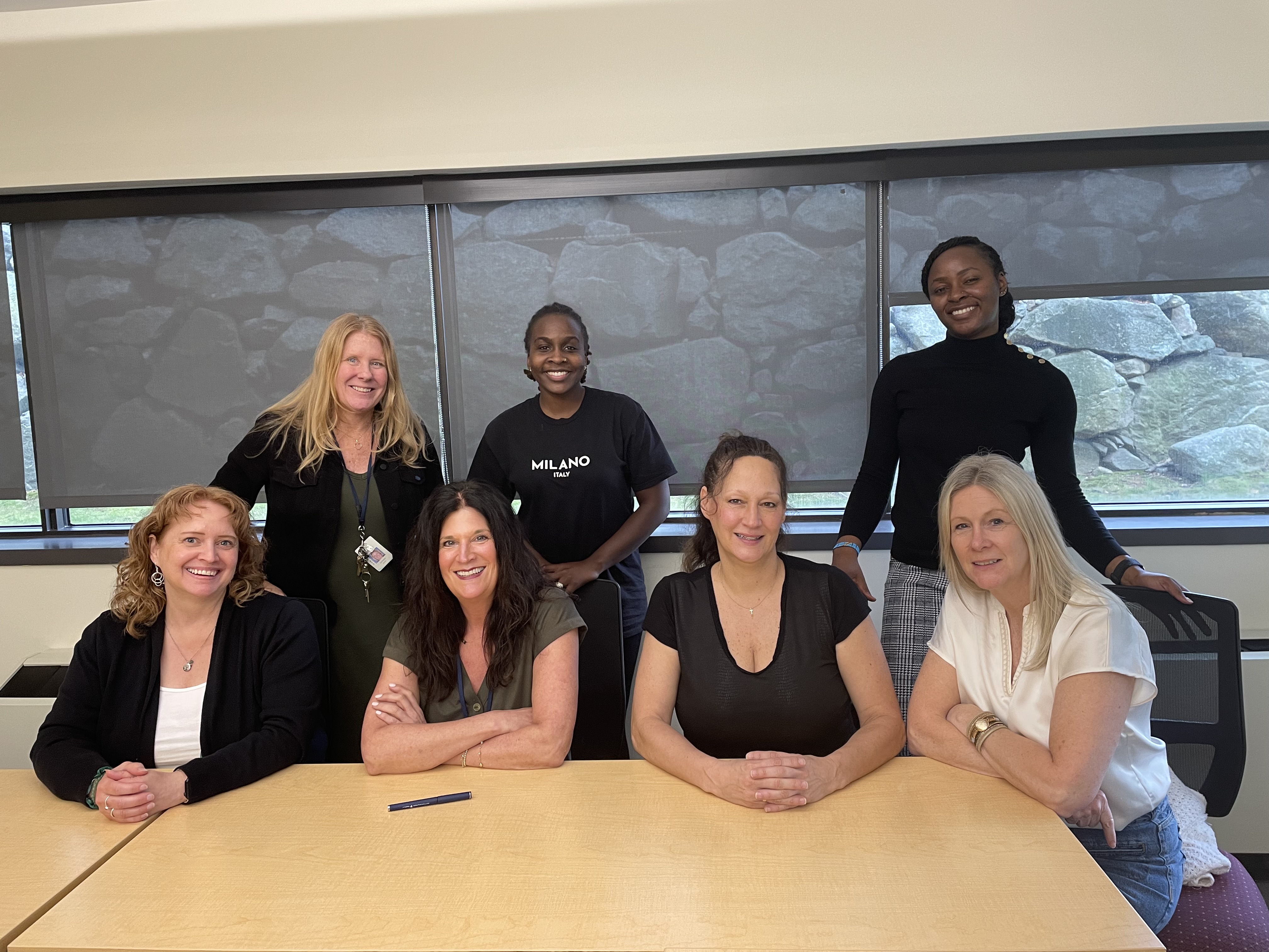 Seven members of The Guild nursing staff gather together around a conference table for a group photo.