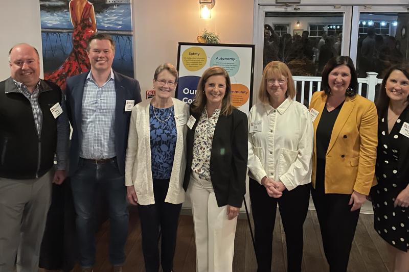 Board members stand together in a line inside a restaurant at an event.