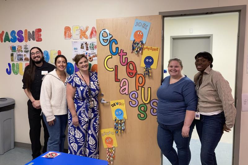 A group of five staff members stand together in a doorway labeled "Octopus Class".