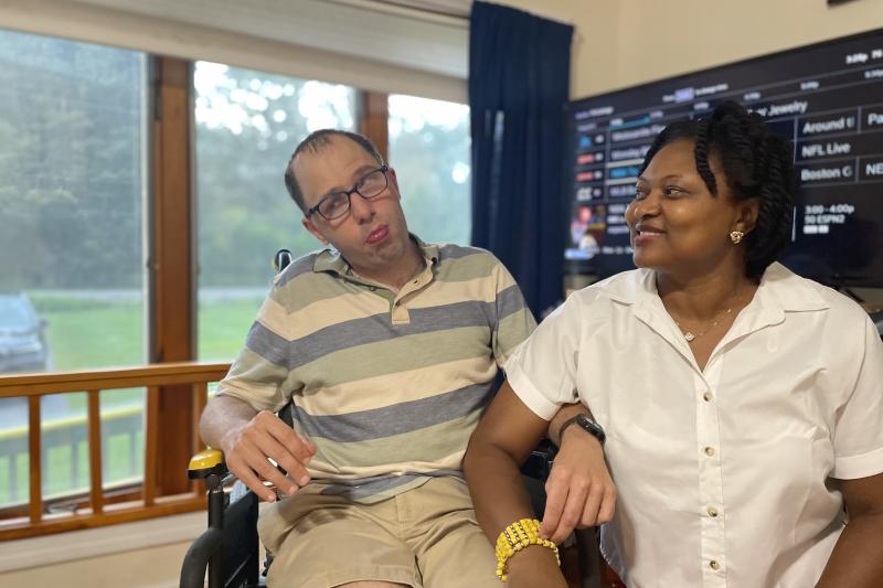 A staff member sits with a resident at his home.