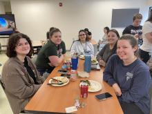 A group of Guild School staff sit together at a table to enjoy the staff appreciation luncheon.