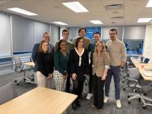 Leadership from The Guild stand together with a team of 5 Oracle-NetSuite employees in a conference room.