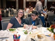 Jeannette and Robbie sit together at a formal dinner table.